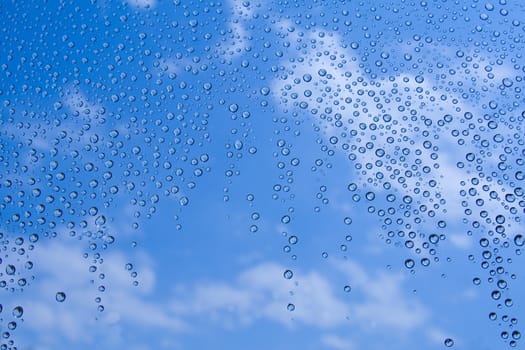 Water drops against blue sky with clouds.