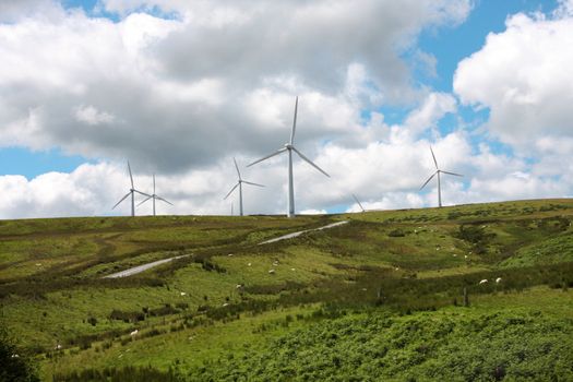 Wind Farm Power Turbines Carno Wales UK against a blue sky with black clouds,rural sheep farming area