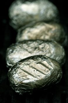 Potatoes wrapped in aluminium sizzling on the BBQ