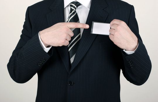 Business man wearing a suit pointing to a blank namebadge - insert your own brand and information