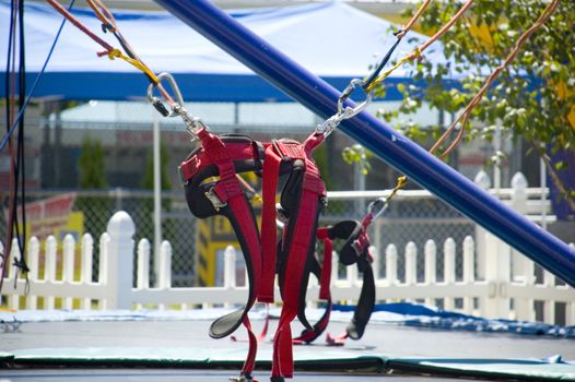 The harness for a trampoline spot support system with trampoline below and circus tent behind.