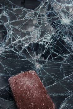 Big brick lying on a completely shattered windshield