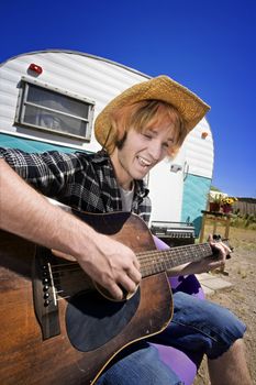 Young Man with Bright Red Hair and a Guitar in front of Trailer