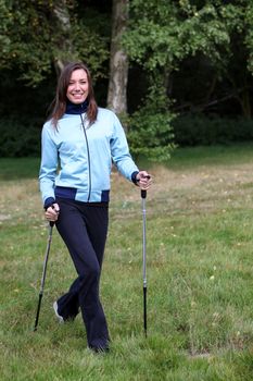 A young woman keeps fit. She tumbles through the woods towards the camera and laughs