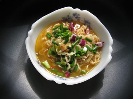 a bowl of instant noodles with spring onion dressing