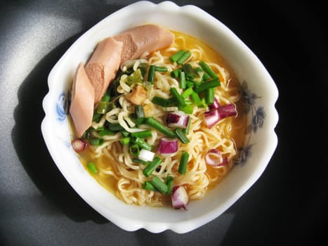 top view for a bowl of instant noodles with spring onion and sausage