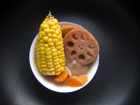 top view for a bowl of soup with lotus, corns, carrot and meats