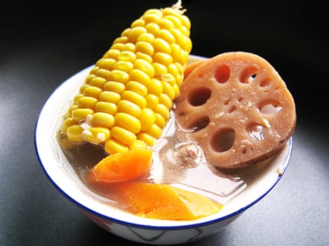 a bowl of soup with lotus, corns, carrot and meats