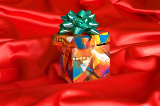 Gift box on a red satin cloth.