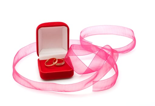 Wedding rings in the red box and a pink ribbon on a white background.
