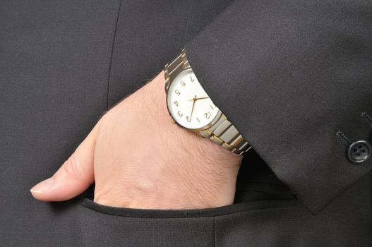 A man in a business suit, put his hand to the clock in the pocket of his jacket