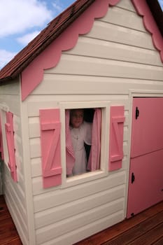 a young girl looking out of a playhouse window on her communion day