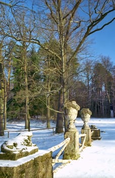Fence with stone vases and ruin of sculpture in winter park