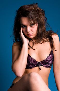 Fresh brunette girl in purple lingerie on blue