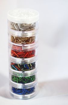 A close up photograph of a pile of jars of decorative bugle beads