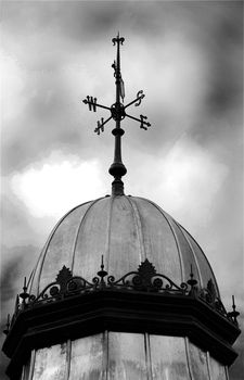A photograph of the points of the compass on a weather vane, in black and white under a moody sky