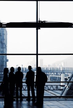 Business people silhouette standing front of windows in modern building.
