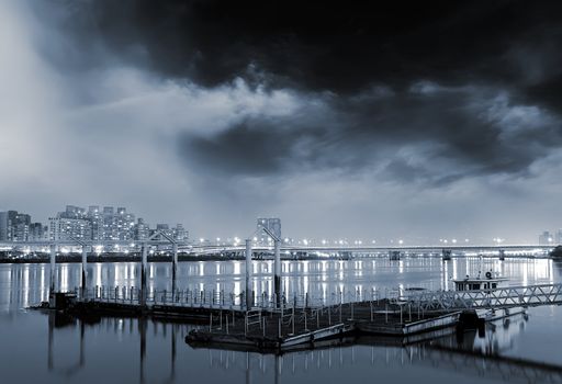 Taipei cityscape of pier by river with buildings light and amazing clouds.