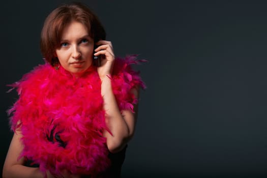 Beautiful woman in pink feathers speaks on phone. Close-up view