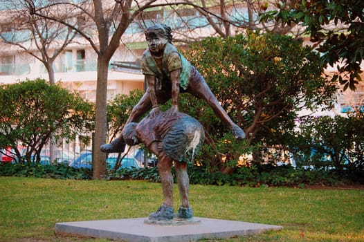 Escultura de dos niños saltando al potro