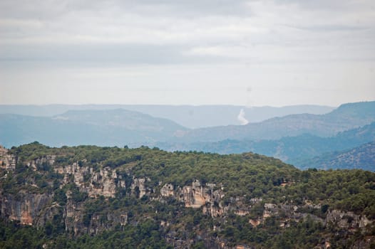 paisaje de montaña con nubes y humo al fondo