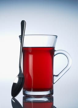 Cup of red fruit tea on light blue background