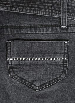 Closeup of black jeans pocket with white stitches.