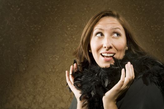 Pretty Hispanic Woman Wearing a Feather Boa in front of Gold Wallpaper