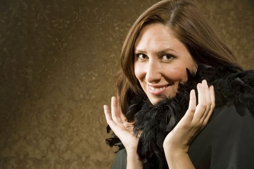 Pretty Hispanic Woman Wearing a Feather Boa in front of Gold Wallpaper