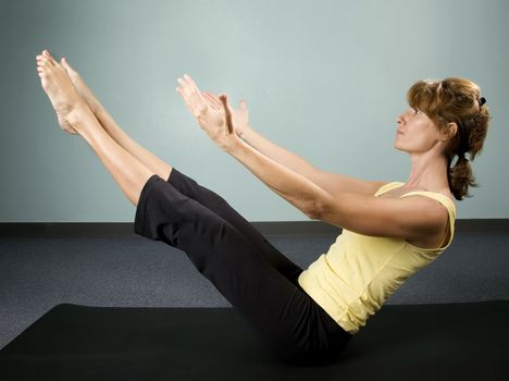 Physically fit young woman doing a balancing excercise on a mat