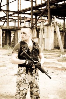 Man in camouflage with gun over metallic construction