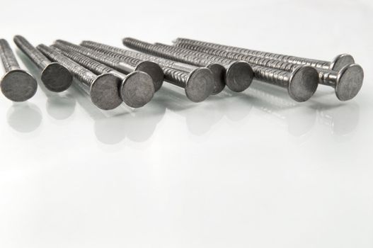 Close and low level angle of a group of steel nails arranged on white.