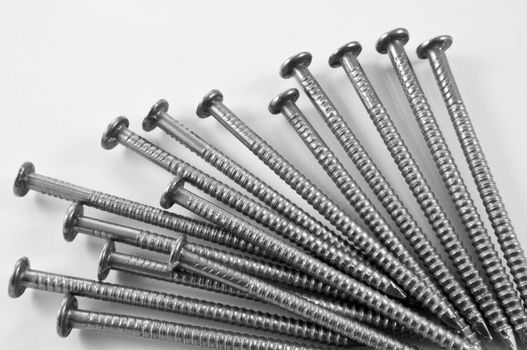 Close up of a group of steel nails arranged over white.