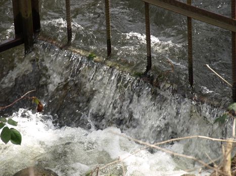 Tight view of a watershed coursing through a gated area.