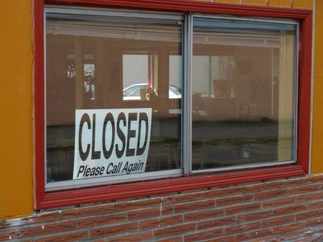 A closed sign rests in the window of a restaurant.