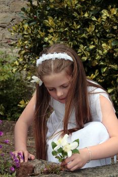 portrait of a young girl on her first communion in ireland picking flowers