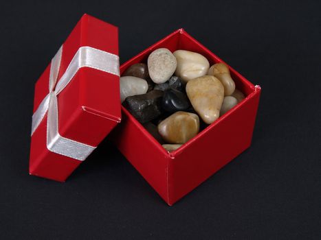 A red box full of polished stones against a black background.