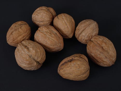 Several walnuts in shells isolated against a black background.