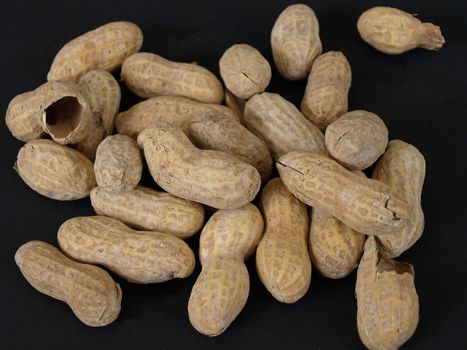 Peanuts laying in a jumble against a black background.