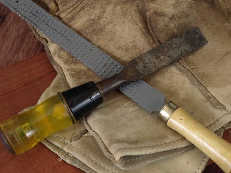 An old chisel and a rasp with a pair of leather work gloves.
