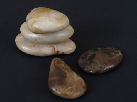 Smooth polished stones stacked and single against a black background.