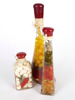 A colorful assortment of pickled spices in different shaped jars on white.