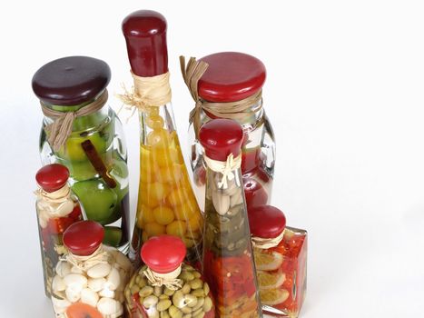 A colorful assortment of pickled spices in different shaped jars on white.