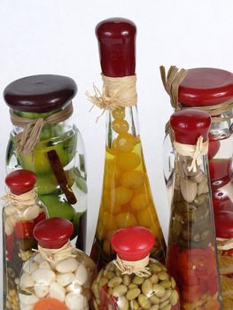 A colorful assortment of pickled spices in different shaped jars on white.
