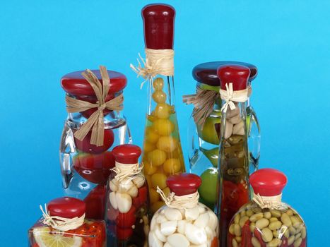 A colorful assortment of pickled spices in different shaped jars over a blue background.