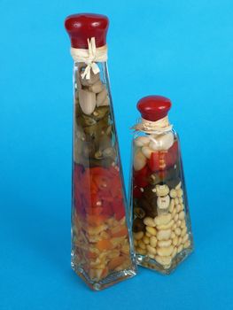 A colorful assortment of pickled spices in different shaped jars over a blue background.