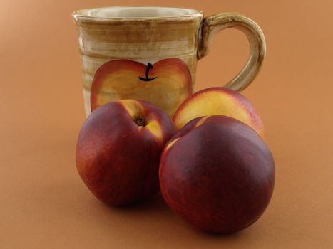 Three ripe peaches with a coffee cup over a light brown background.