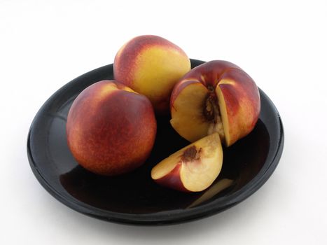 Whole and sliced juicy peaches isolated on a black plate