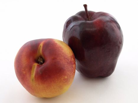 Ripe juicy peach and crisp red apple isolated against a white background