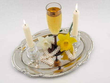 White wine and candles with white pearls on a silver tray isolated on a white background